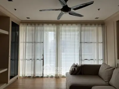 Spacious living room with large windows and modern ceiling fan