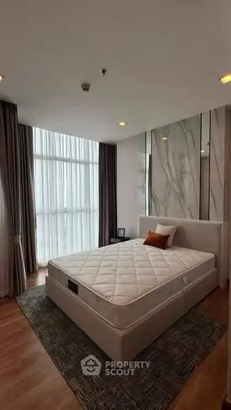 Spacious bedroom with modern decor and large windows for natural light.