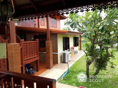 Charming traditional wooden house with lush garden and intricate balcony design.