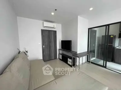 Modern living room with sleek furniture and glass sliding doors leading to kitchen.
