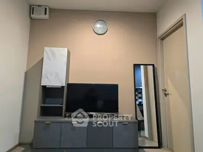Modern living room with sleek TV stand and wall-mounted clock, showcasing minimalist design.