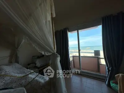 Cozy bedroom with canopy bed and stunning ocean view from balcony.