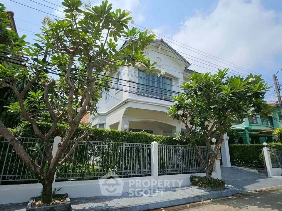 Charming two-story house with lush garden and elegant white fence in a serene neighborhood.