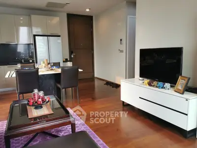 Modern living room with wooden flooring, stylish furniture, and open kitchen layout in a high-rise apartment.