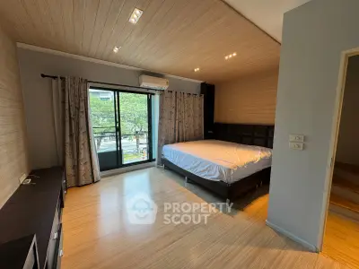 Spacious bedroom with modern design and large window overlooking greenery, featuring elegant wood flooring and ceiling.