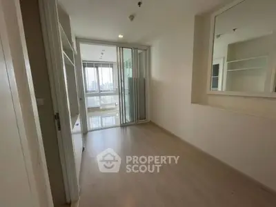 Spacious empty room with sliding glass doors and city view.