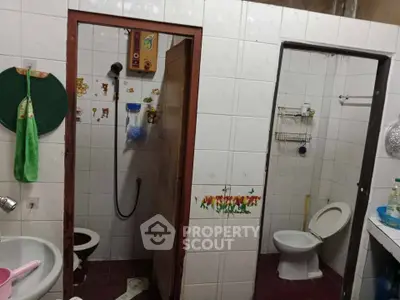 Functional bathroom with separate shower and toilet areas, featuring tiled walls and essential fixtures.