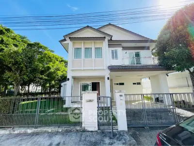 Charming two-story house with lush garden and gated entrance in a serene neighborhood.