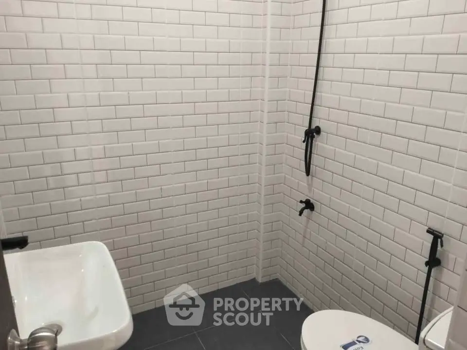 Modern minimalist bathroom with white subway tiles and sleek fixtures.