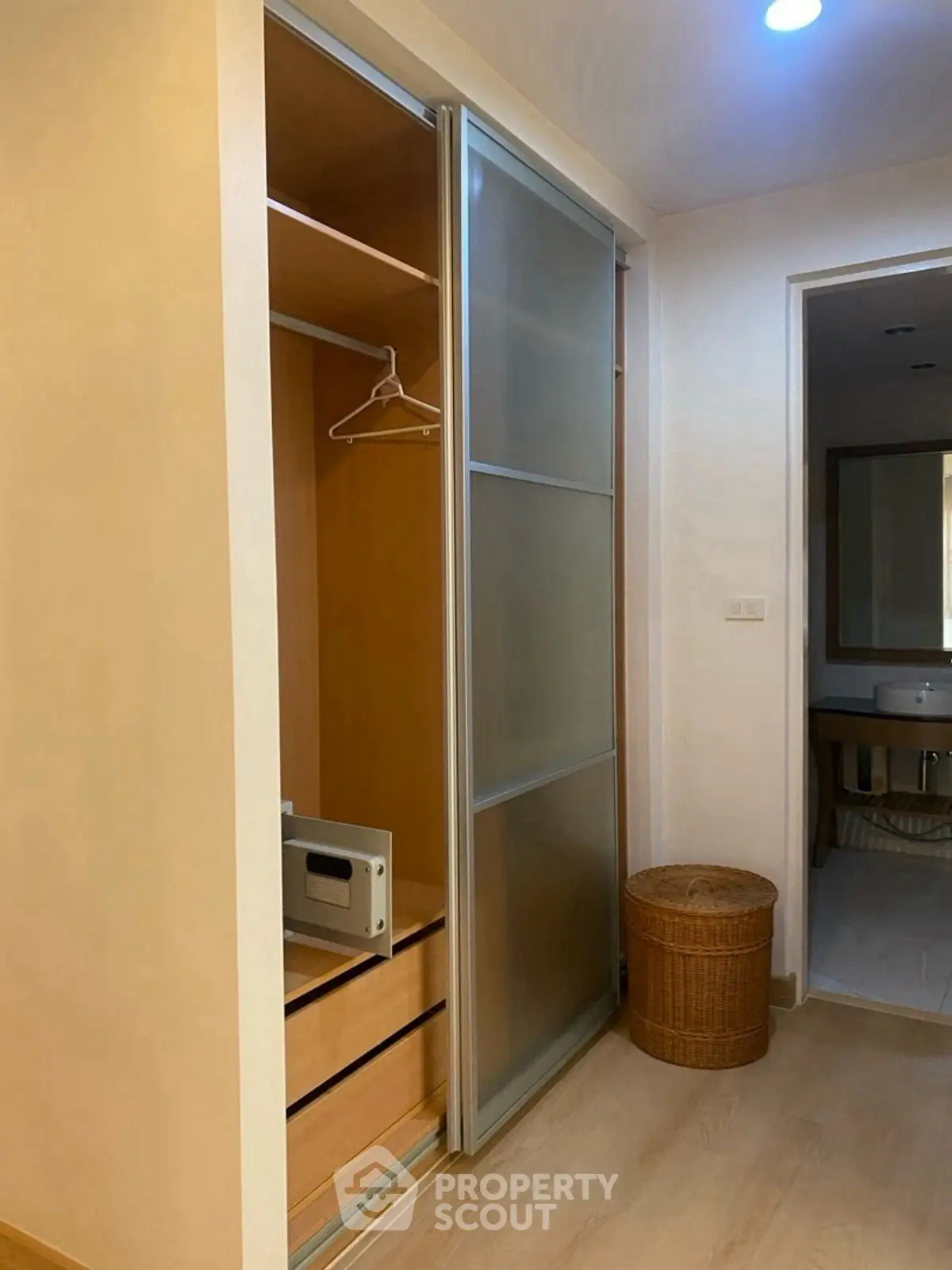 Modern apartment with built-in closet and bathroom view, featuring sleek sliding doors and warm lighting.