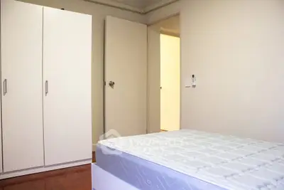 Spacious bedroom with white wardrobe and comfortable mattress, ideal for restful nights.