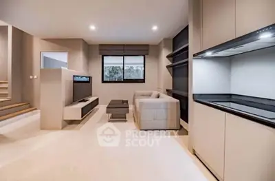 Modern open-plan living room with sleek kitchen and cozy seating area, perfect for contemporary living.