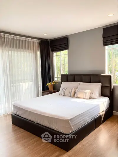 Spacious bedroom with modern decor and large windows for natural light