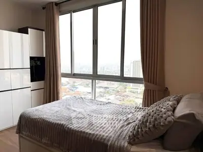 Cozy bedroom with large window offering stunning city views, perfect for relaxation and comfort.