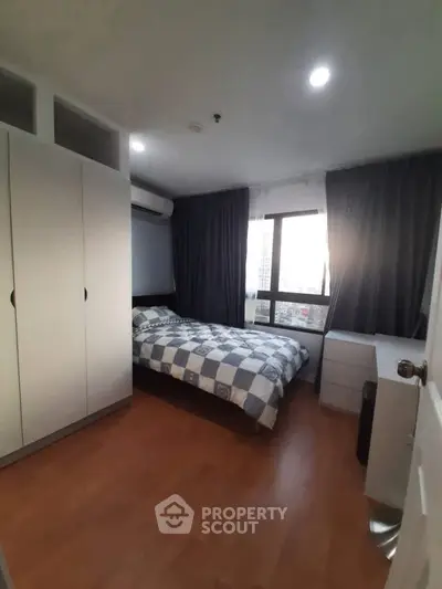 Cozy bedroom with wooden flooring and large window in modern apartment