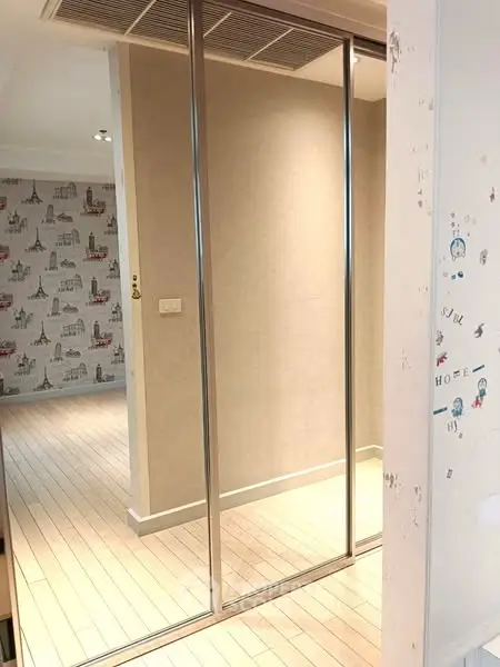 Modern interior with sliding mirrored closet doors and stylish wallpaper accent.