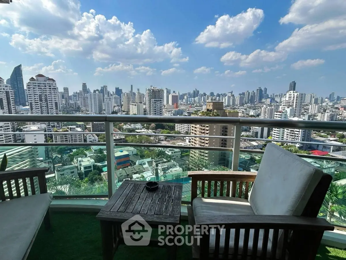 Stunning cityscape view from a high-rise balcony with cozy seating area.