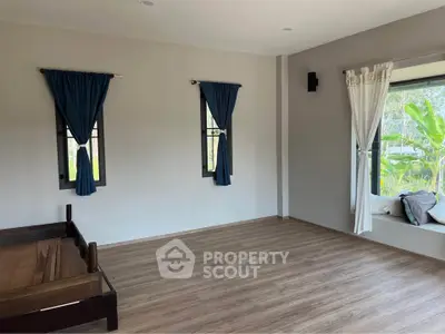 Spacious bedroom with large windows and wooden flooring