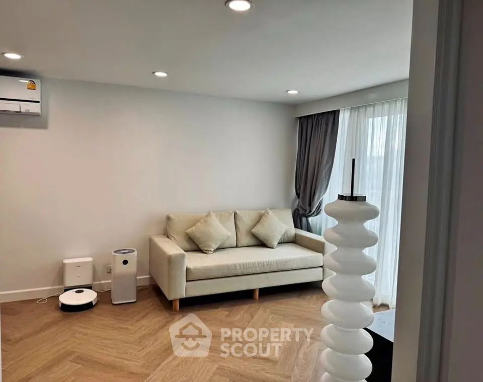 Modern living room with stylish sofa and wooden flooring, featuring smart home devices.