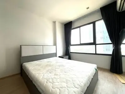Spacious bedroom with large windows and modern decor in a high-rise apartment.
