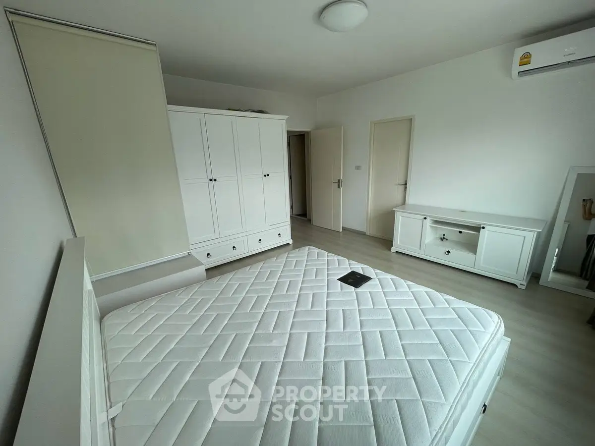 Spacious bedroom with modern white furniture and ample natural light, perfect for a serene living experience.