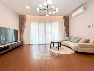 Spacious living room with elegant chandelier and modern furnishings, perfect for relaxation and entertainment.