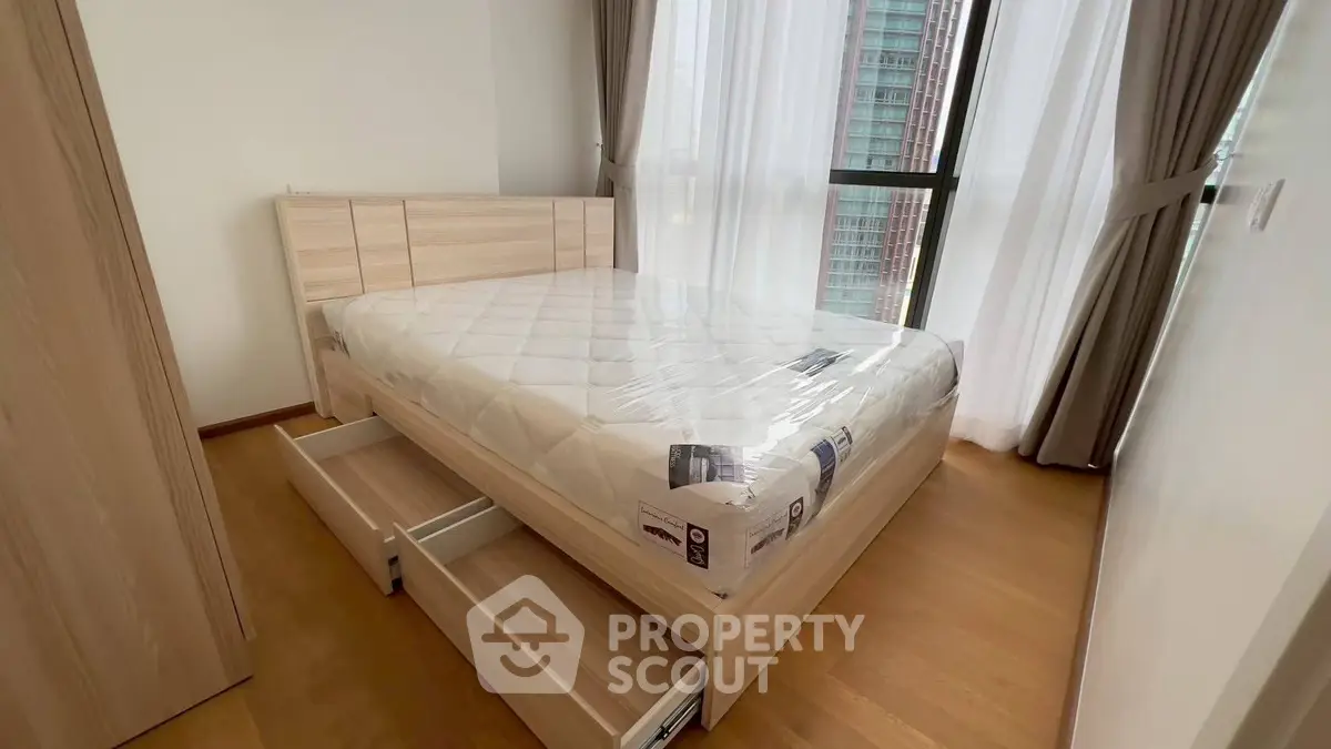 Modern bedroom with wooden flooring and large windows in a high-rise apartment.