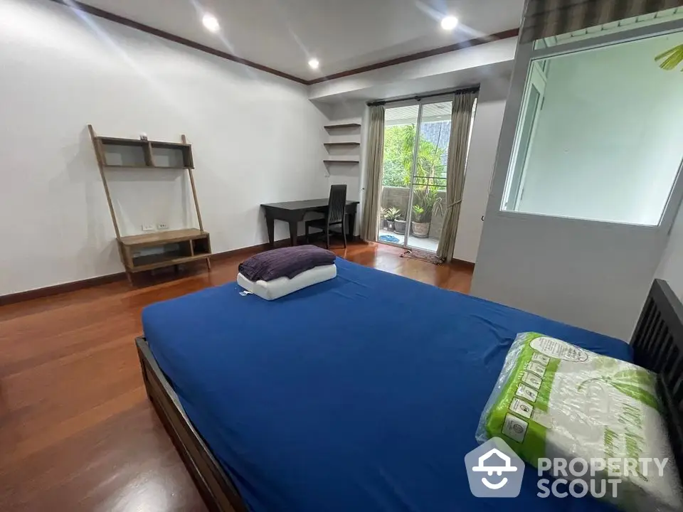 Spacious bedroom with wooden flooring and balcony access