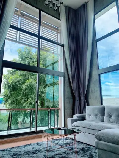 Luxurious living room with floor-to-ceiling windows and plush gray sofa.