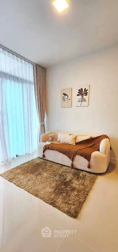 Modern living room with cozy sofa, elegant decor, and large window for natural light.