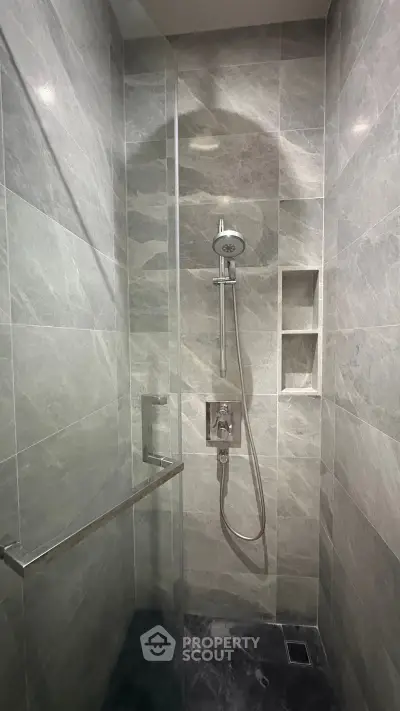 Modern bathroom shower with sleek marble tiles and built-in shelving