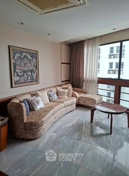 Elegant living room with plush sofa and large windows offering city views.