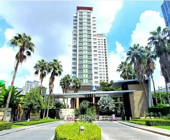 Luxurious high-rise building with palm-lined entrance and lush landscaping.