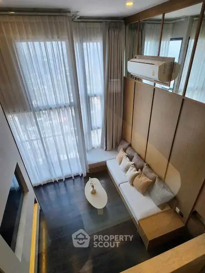 Modern living room with high ceilings and large windows offering stunning city views.