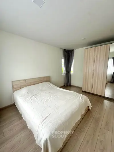 Spacious bedroom with modern wooden wardrobe and large window for natural light.