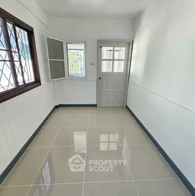 Bright empty room with tiled floor and large window, ideal for customization.