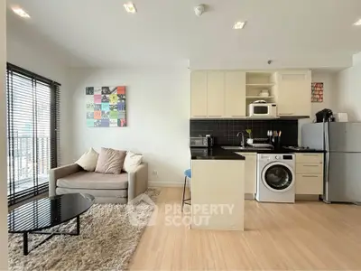 Modern open-plan living room with kitchen, featuring sleek appliances and cozy seating area.