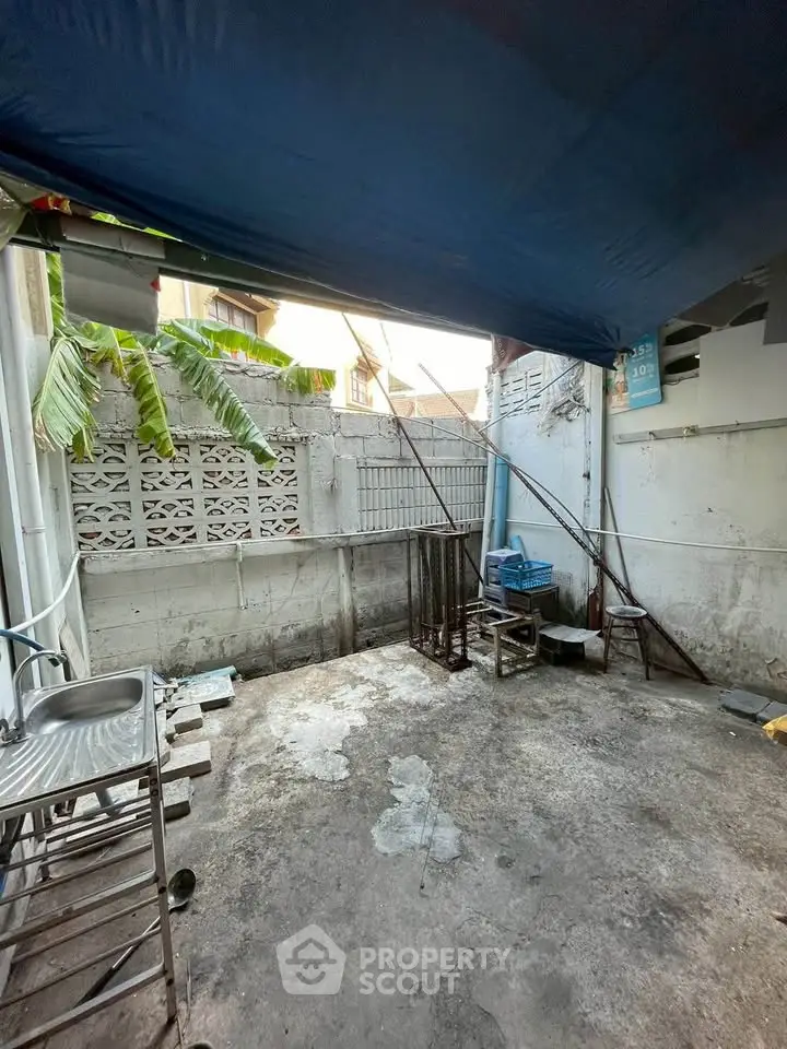 Spacious outdoor area with potential for renovation, featuring a sink and partial covering.