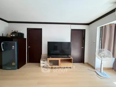 Spacious living room with modern TV setup and sleek wooden flooring