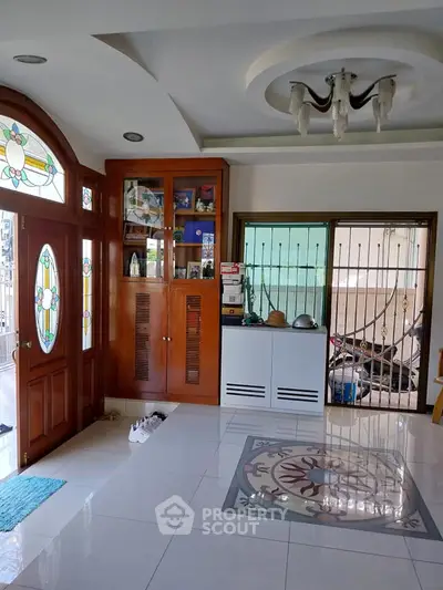 Charming living room with stained glass door and elegant ceiling light fixture.