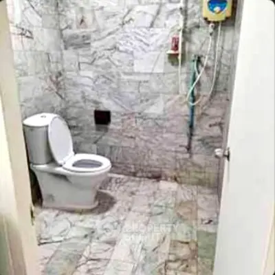 Spacious marble-tiled bathroom with modern toilet and shower setup.