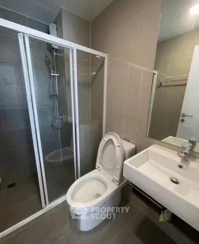 Modern bathroom with glass shower and sleek fixtures in contemporary apartment.