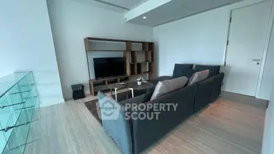 Modern living room with sleek furniture and minimalist design, featuring a large TV and stylish shelving unit.