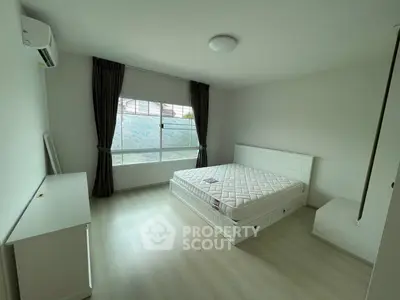 Spacious bedroom with large window and minimalist decor in modern apartment