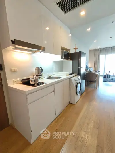 Modern kitchen with sleek white cabinets, integrated appliances, and open layout leading to dining area.