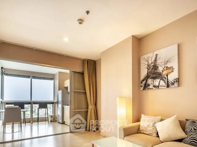 Modern living room with open kitchen and large windows offering natural light.