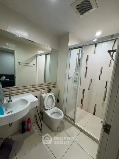 Modern bathroom with glass shower and sleek fixtures in contemporary apartment.