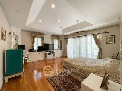 Spacious bedroom with wooden flooring, large windows, and elegant decor in a modern home.
