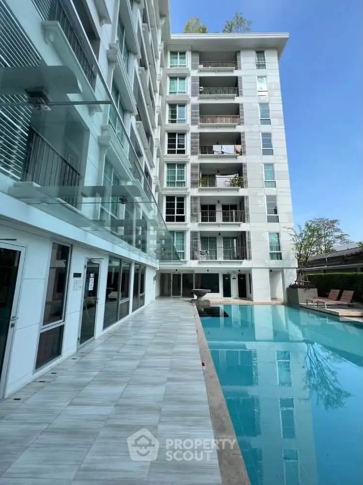 Modern apartment building with poolside view and sleek glass balconies.