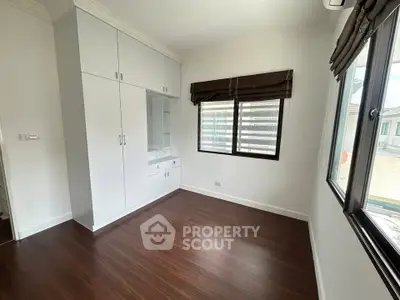 Spacious bedroom with built-in wardrobe and large windows in modern home